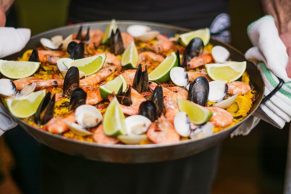 A dish of paella with shrimp, mussels, and lemon