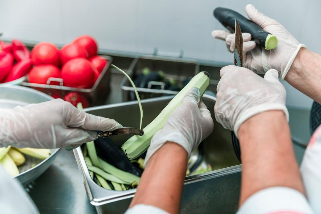 Workers peel and cut vegetables as part of source strategies for small food manufacturing businesses.
